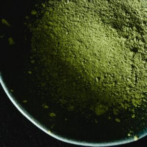 Intriguing close-up of matcha powder in a bowl against a dark background, highlighting texture.